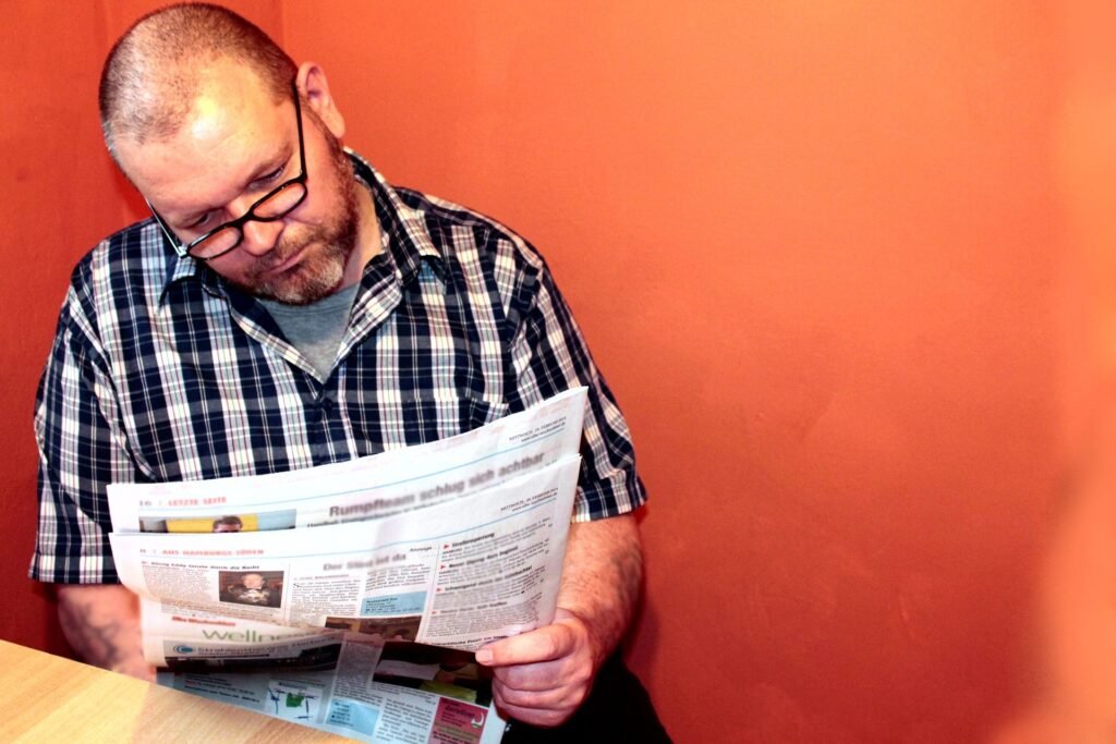 A man with glasses reading a newspaper A man with glasses reading a newspaper