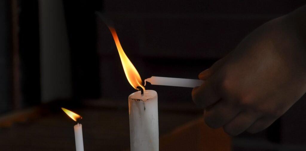 Someone using a candle to light another candle Someone using a candle to light another candle