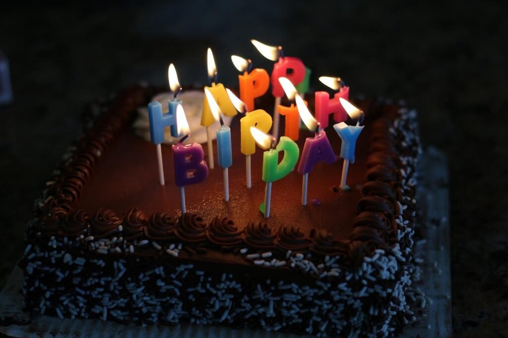 A cake with lit birthday candles spelling out "happy birthday" A cake with lit birthday candles spelling out "happy birthday"