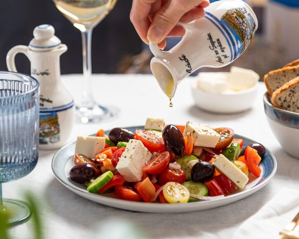 A greek salad with dressing being poured on A greek salad with dressing being poured on
